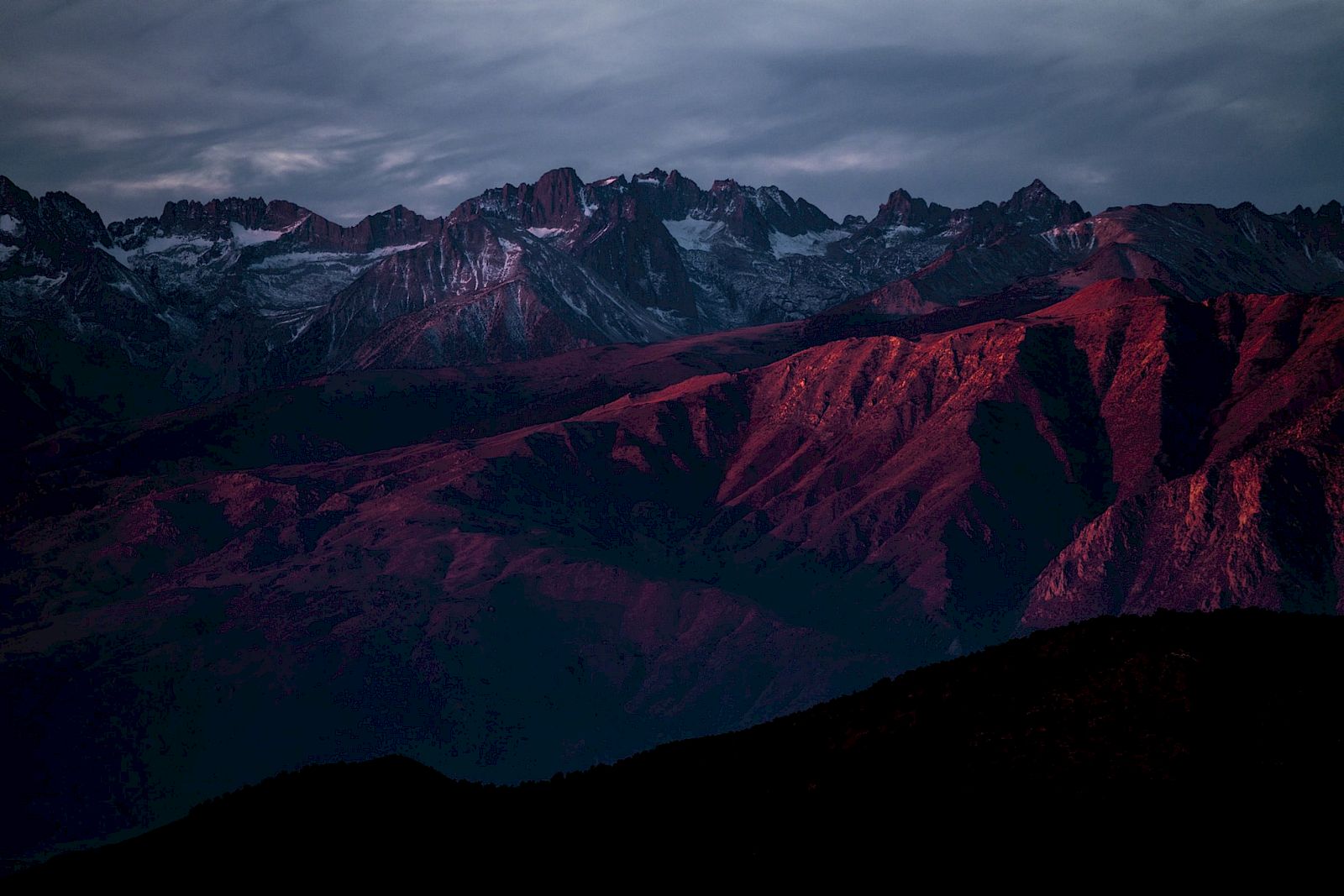 A mountain range bathed in the glow of sunset, with dramatic shadows and rugged peaks.