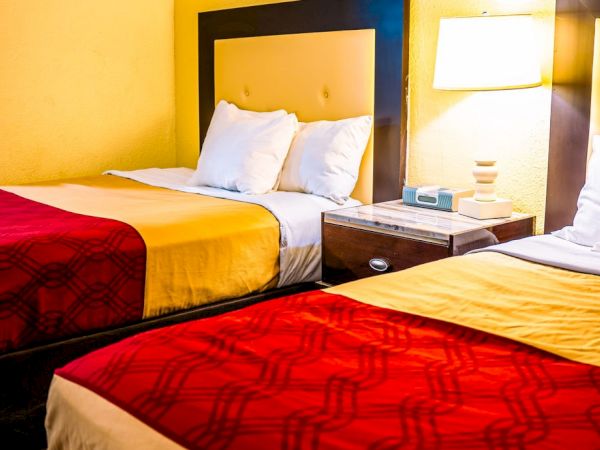 The image shows a hotel room with two beds, a lamp, and a nightstand between them.