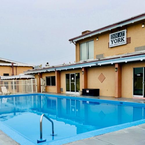 The image shows a hotel with a sign reading "Inn at York" and a clear blue swimming pool in front, surrounded by a patio area.