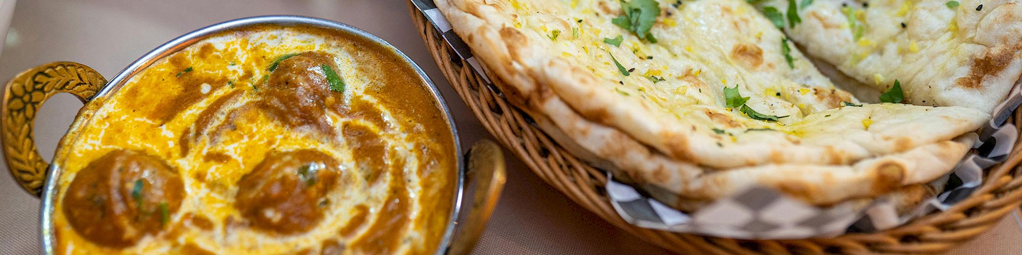 The image shows Indian cuisine, including naan bread, a curry dish with meatballs, and a spiced vegetable dish.