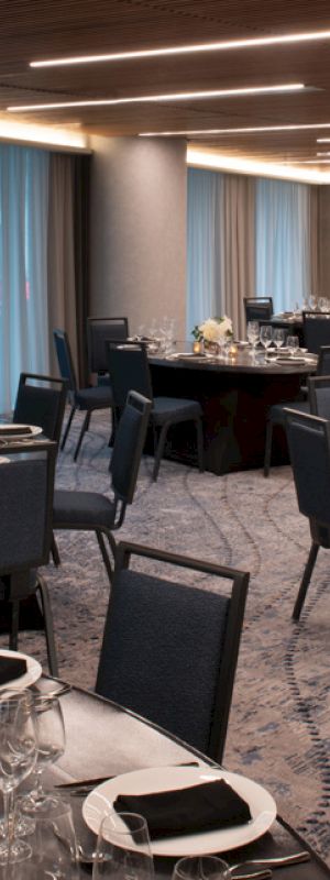 A stylish banquet hall with round tables set for an event, featuring elegant table settings and modern decor.